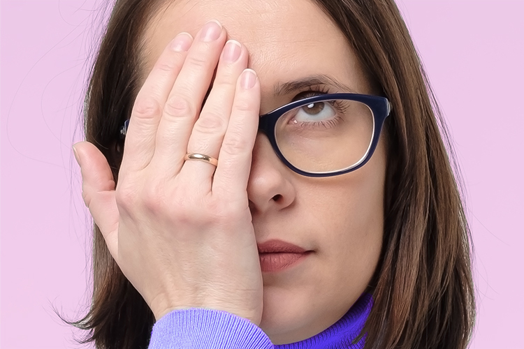 Mujer con gafas ocultando con la mano un orzuelo en el ojo.